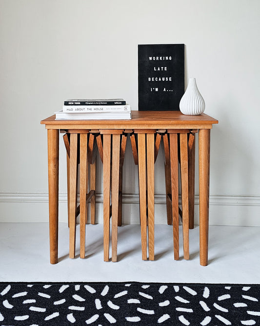 Set of Mid Century Retro Teak tables by Paul Hundevad. One larger table with 3 smaller tables underneath; staged with books and white pottery.